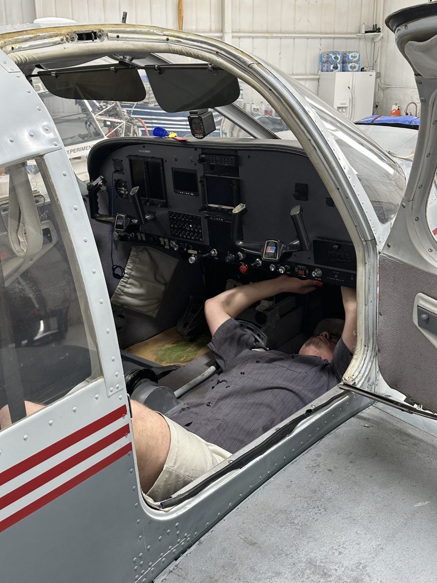 Technician working under the instrument panel of a general aviation aircraft at Mach Aircraft Maintenance